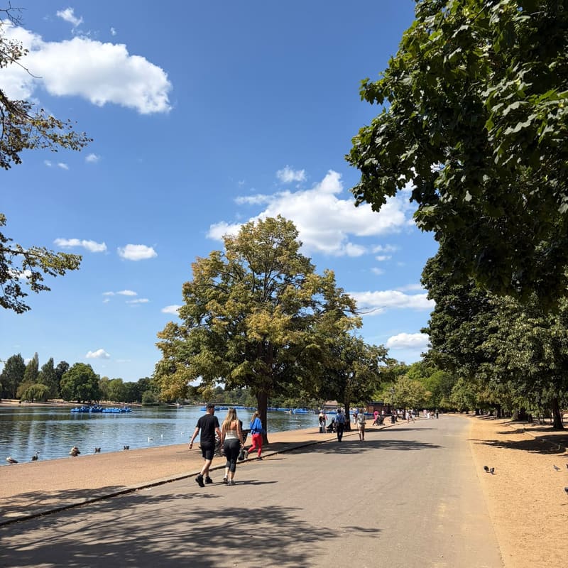 People walking beside the Serpentine in Hyde Park, London, on a sunny day